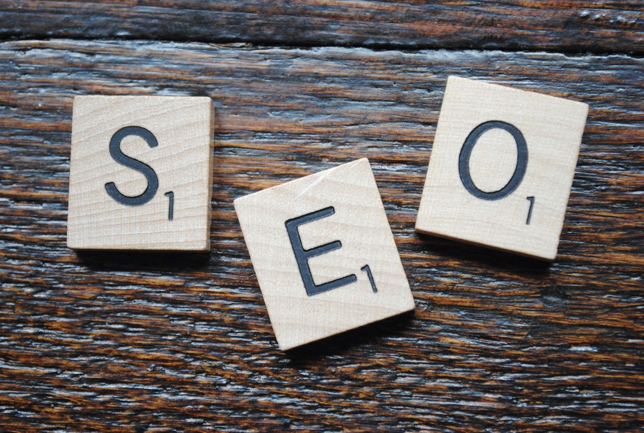 Close-up view of Scrabble tiles arranged to spell SEO on a wooden tabletop for content strategy.